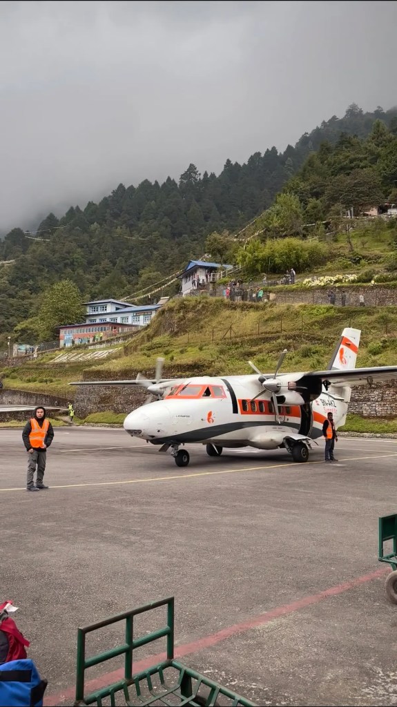 Small Summit Air aircraft on runway at Tenzing-Hillary Airport Lukla Nepal with mountain and forest in background